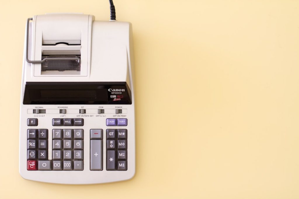 A grey printing calculator on a light yellow background